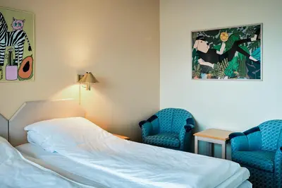 a bedroom with a bed and two blue chairs at Balestrand Hotel in Balestrand