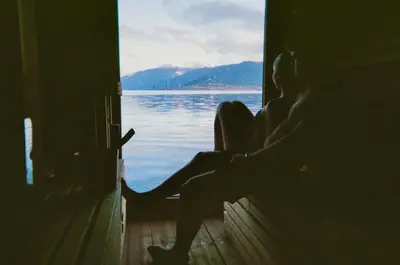 a person sitting on a door looking out at the water at Balestrand Hotel in Balestrand