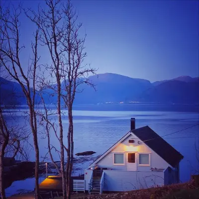 a house on the shore of a lake at night at Waerholmen in Lavik