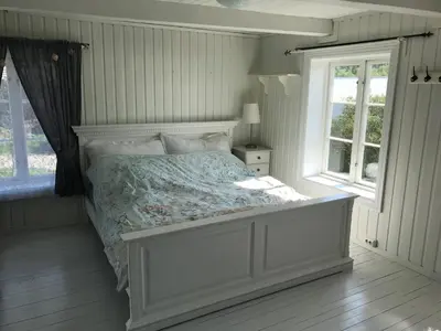 a bedroom with a bed and two windows at Landlig idyll med fjordutsikt in Valsøybotn