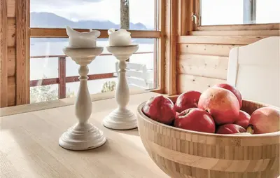 two white candlesticks on a table with a bowl of apples at Gorgeous Home In Norheimsund With Wifi in Norheimsund