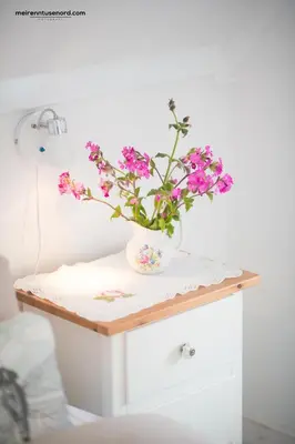 a table with a vase of flowers on it at Kalvåg Holidayapartment in Kalvåg