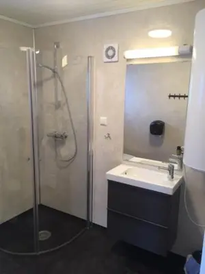 a bathroom with a shower and a sink and a mirror at Røldal Hyttegrend & Camping in Røldal