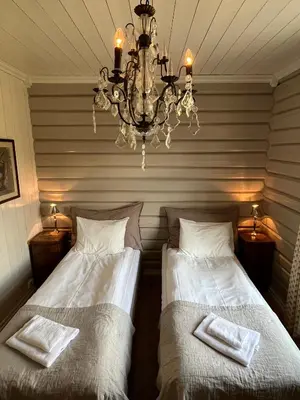 two beds in a room with a chandelier at Eggedal Borgerstue in Eggedal
