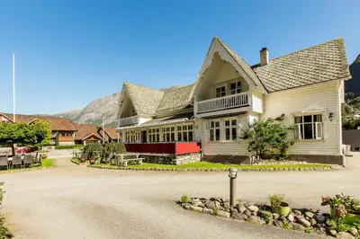 a large white house with mountains in the background at Vik Pensjonat in Eidfjord