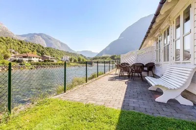 a building with a table and chairs next to the water at Vik Pensjonat in Eidfjord