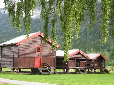 two wooden buildings with red doors in a field at Hagaled Gjestegård in Nesbyen