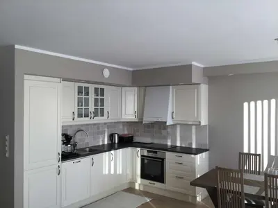a white kitchen with white cabinets and a table at Geilo Superior leilighet in Geilo