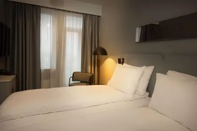 a hotel room with a white bed and a chair at Scandic Victoria Lillehammer in Lillehammer