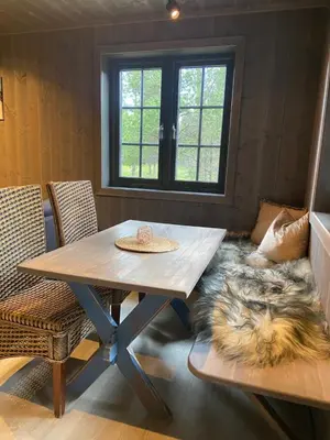 a wooden table and chairs in a room with a rug at Jotunheimen Husky Lodge in Randsverk