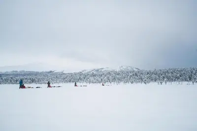 a group of people standing on a snow covered field at Jotunheimen Husky Lodge in Randsverk