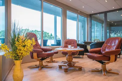 a waiting room with chairs and a table and windows at Almaas Hotell Stord AS in Stord