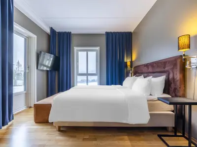 a bedroom with a large white bed and blue curtains at Radisson Blu Resort, Trysil in Trysil
