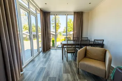 a dining room with a table and chairs and large windows at Sveastranda Camping in Gullor