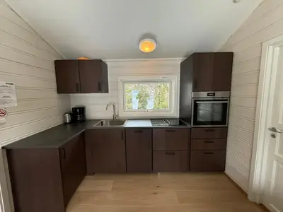 a kitchen with wooden cabinets and a sink and a window at Sveastranda Camping in Gullor