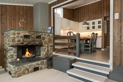 a kitchen and living room with a stone fireplace at Bitigrenda N in Beitostøl