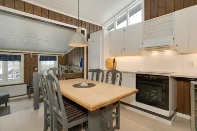 a kitchen and dining room with a wooden table and chairs at Bitigrenda N in Beitostøl