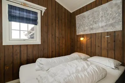 a bedroom with a bed with wooden walls and a window at Bitigrenda N in Beitostøl