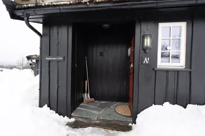 a black cabin with a door in the snow at Bitigrenda N in Beitostøl