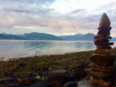 a stack of rocks on the shore of a lake at Cosy chalet, 100m2 with fjordview! in Lauvstad