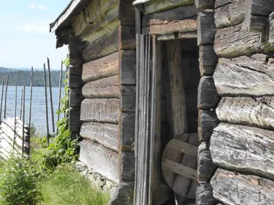 an open door of an old stone building with water in the background at Vestre Sorken Feriegard in Drevsjø