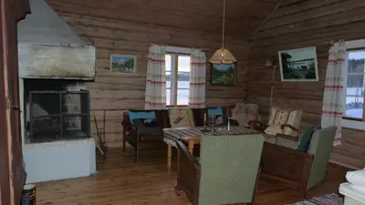 a living room with a fireplace and a table and chairs at Vestre Sorken Feriegard in Drevsjø