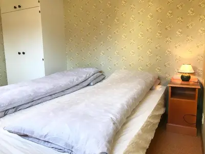 a bedroom with two beds and a night stand with a lamp at Villa Holmen 2 - Ground floor apartment in Balestrand