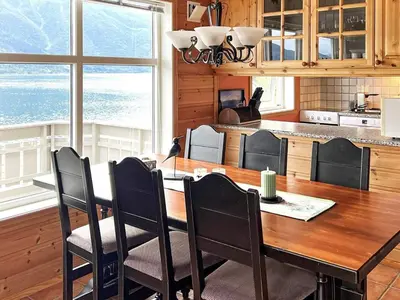 a kitchen with a wooden table with chairs and a large window at 6 person holiday home in Leikanger in Leikanger