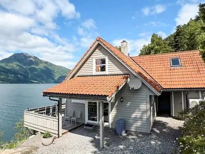 a house with an orange roof next to a lake at 6 person holiday home in Leikanger in Leikanger
