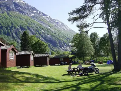 a group of people sitting at a picnic table in the grass at Mindresunde Camping in Mindresunde