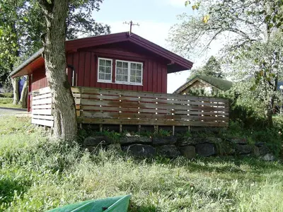 a small red house with a tree in front of it at Mindresunde Camping in Mindresunde