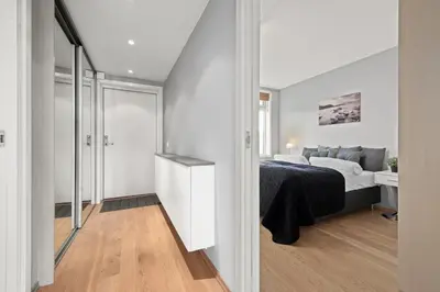 a white bedroom with a bed and a bathroom at BJØRVIKA APARTMENTS, Solsiden Area, Trondheim city center in Trondheim