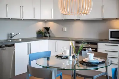 a kitchen with a glass table and chairs at BJØRVIKA APARTMENTS, Solsiden Area, Trondheim city center in Trondheim
