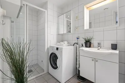 a white bathroom with a washing machine and a sink at BJØRVIKA APARTMENTS, Solsiden Area, Trondheim city center in Trondheim
