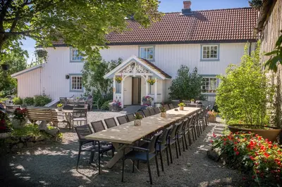 a table and chairs in front of a white house at Klostergården Bed & Breakfast in Tautra