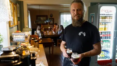 a man standing in a bar holding a glass of wine at Klostergården Bed & Breakfast in Tautra