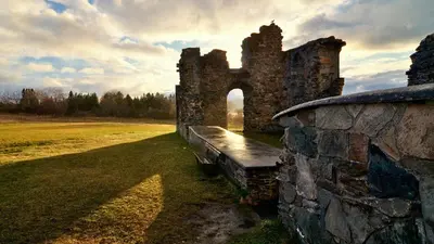 an old stone building with a bench in a field at Klostergården Bed & Breakfast in Tautra