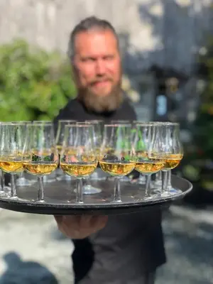 a man holding a tray of wine glasses at Klostergården Bed & Breakfast in Tautra