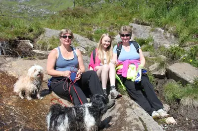 three women sitting on a rock with their dogs at Sunndalsfjord Cottages Fredsvik Meisalstranda 455,506 og 508 in Sunndalsøra