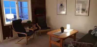 a living room with a table and chairs and a window at Oppdal Alpintun Stølen ski in - ski out in Oppdal