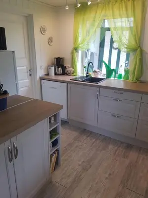 a kitchen with white cabinets and a sink and a window at Lille Villa Severin in Mosterhamn