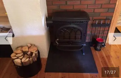 a fireplace with a trash can and a basket of logs at Sjoaasen Hytte in Tuddal