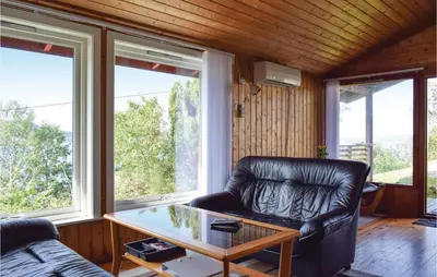 a leather chair and a table in a room with windows at Lovely Home In Sandvoll With Wifi in Sandvoll