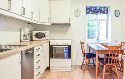 a kitchen with white cabinets and a table and chairs at Awesome Home In Holmefjord in Holmefjord