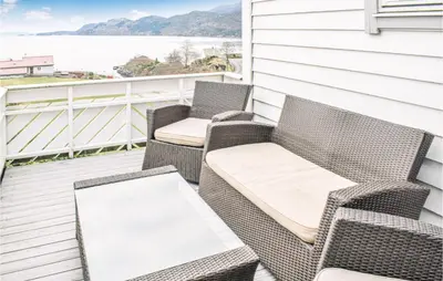 two wicker chairs and a table on a balcony at Awesome Home In Holmefjord in Holmefjord