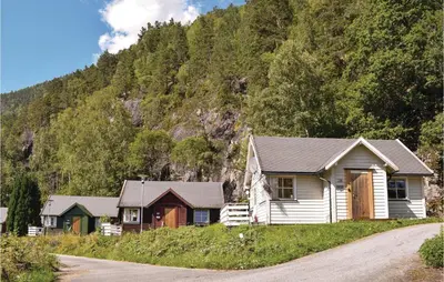 a group of houses on a road next to a mountain at 3 Bedroom Lovely Home In Vallavik in Vangsbygd