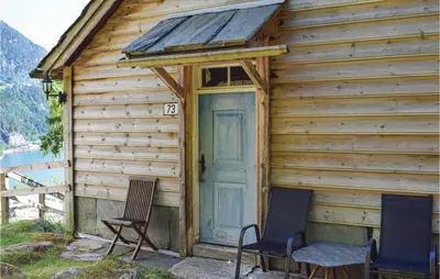 a wooden cabin with two chairs and a door at 1 Bedroom Cozy Home In Vallavik in Kaland