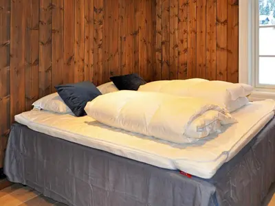 a large bed with white sheets and pillows on it at 12 person holiday home in Fåvang in Favang