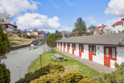 a building with red and white doors and a bench at Midttun Motell & Camping AS in Bergen