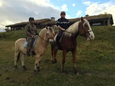 two people riding on horses in a field at Rondaplassen in Kvam
